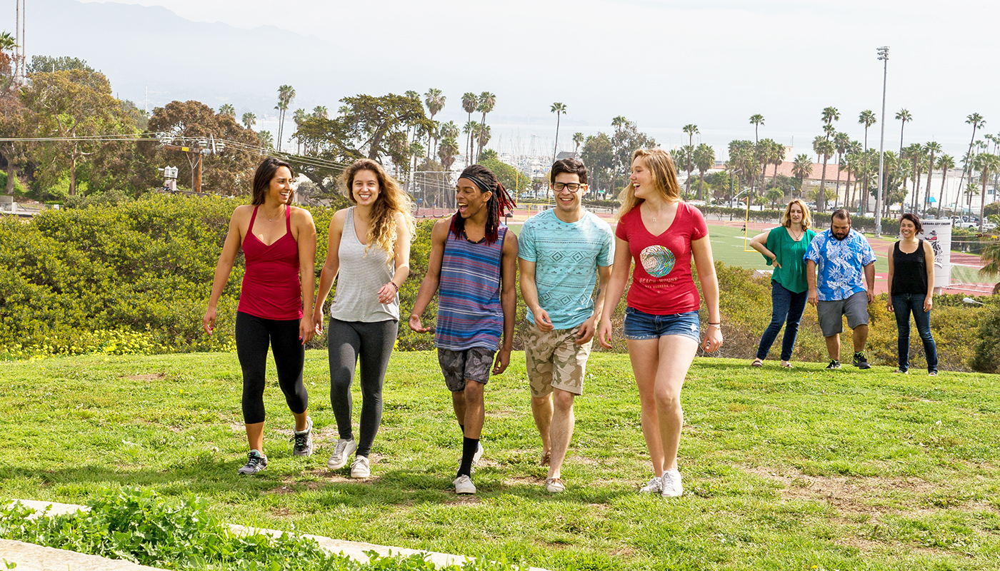 Students on West Campus walking with the Santa Barbara harbor in the background.